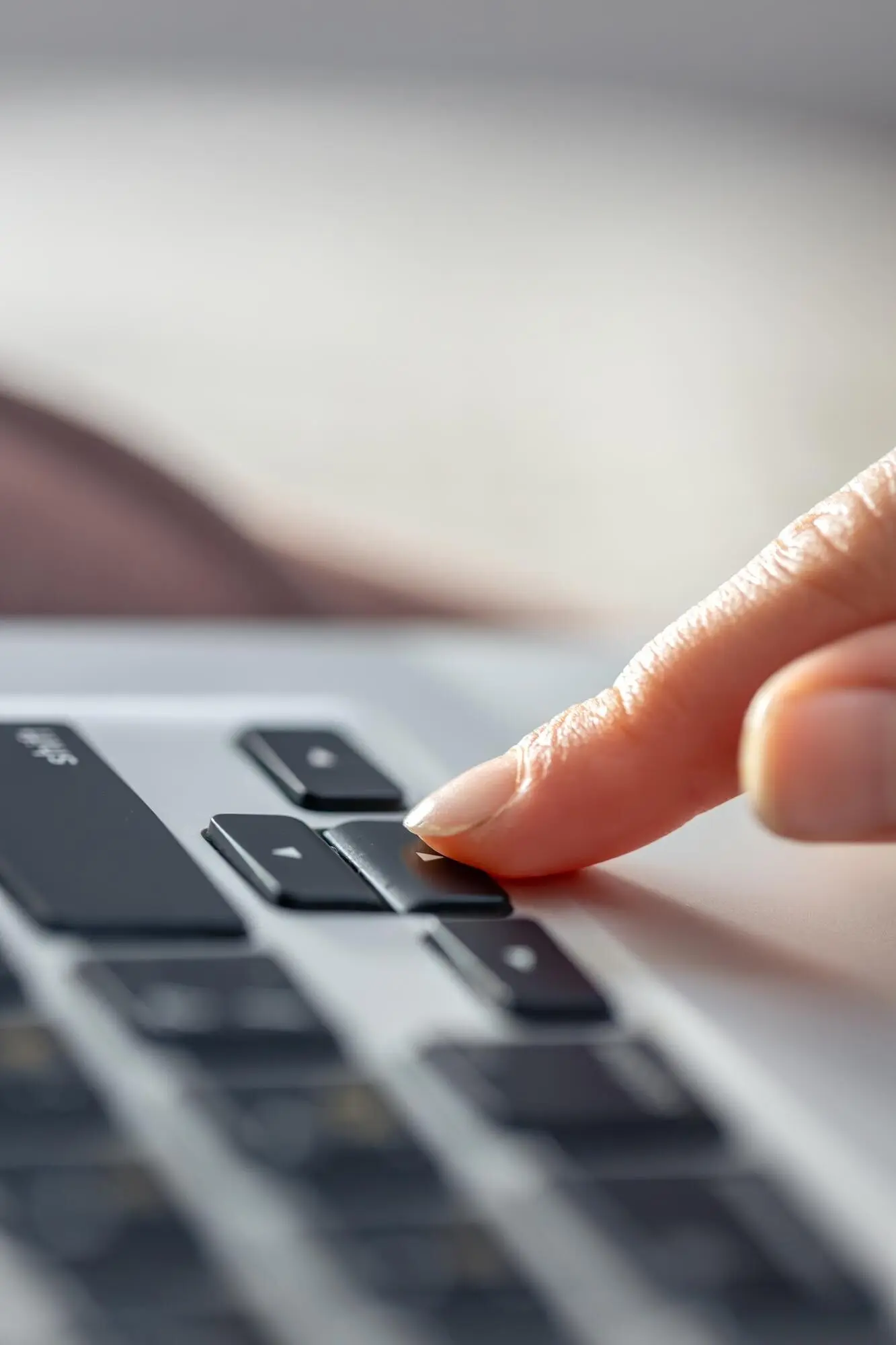 Dívka píše na klávesnici notebooku. Dívčiny ruce jsou na klávesnici.